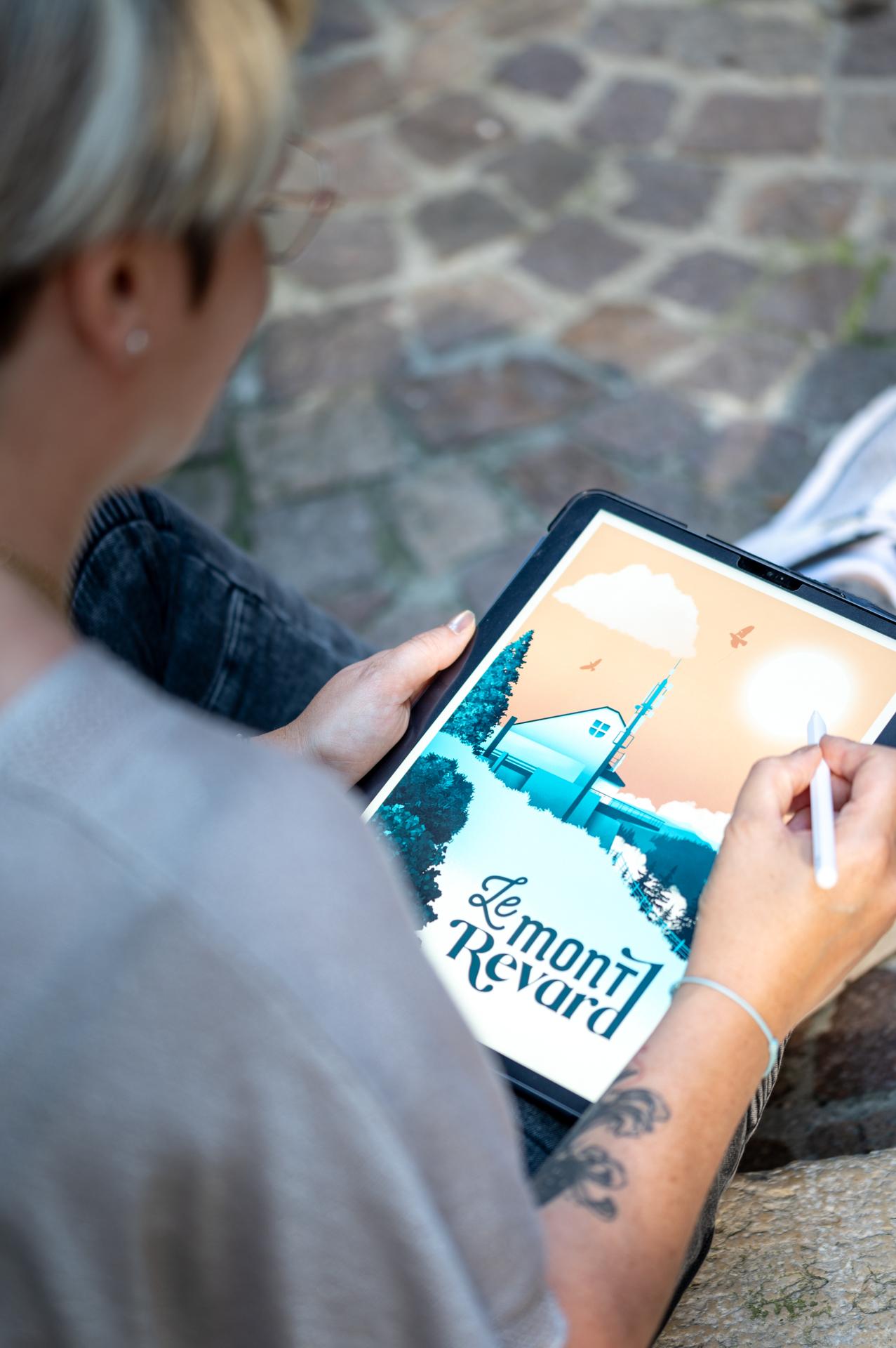 Une graphiste dessine sur tablette numérique une illustration du Mont Revard, style affiche vintage, pour la marque Enemesis and Art.