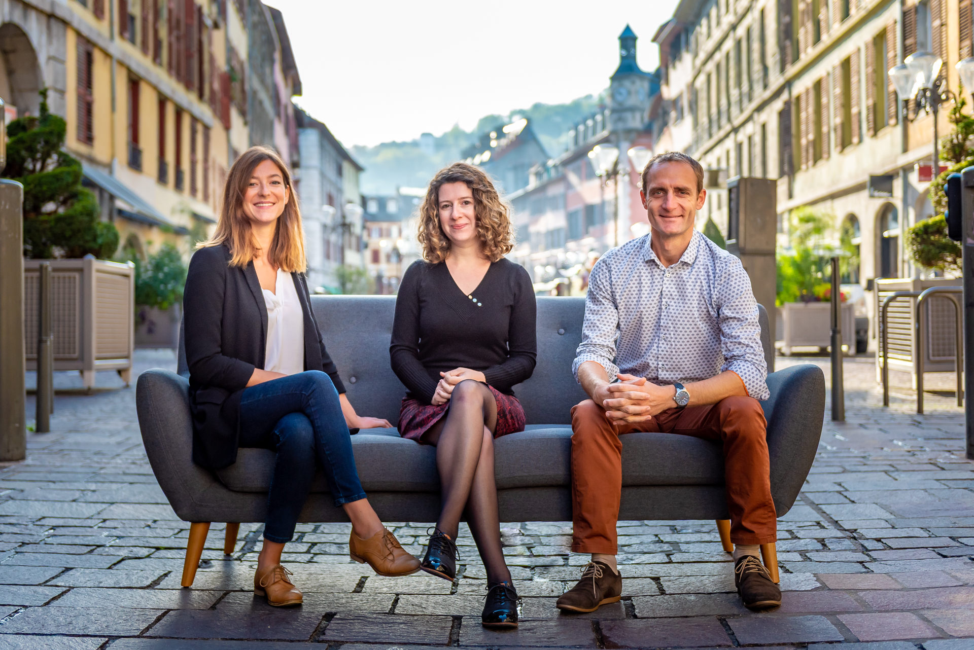 Photo d'équipe de trois personnes assises sur un canapé au milieu d'une rue piétonne de Chambéry, réalisée par Pict'Your Company